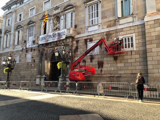 Workers removing red paint from the façade of the Catalan government headquarters (by Cristina Tomàs White)